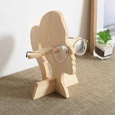 a pair of glasses sitting on top of a wooden stand next to a potted plant