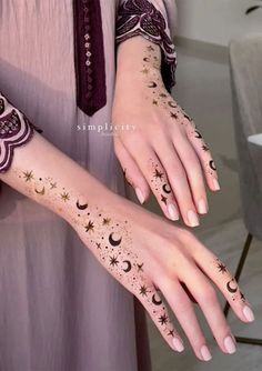 a woman's hands with hendix and stars painted on her arm,