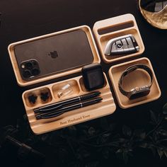 an assortment of cell phones and accessories are arranged in wooden trays on a table