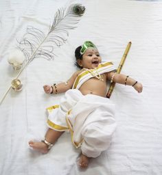 a baby is laying down with a feather on it's head and holding a stick