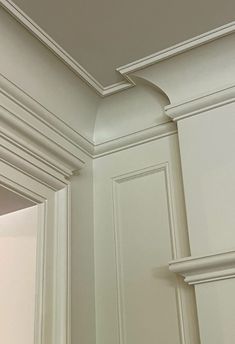 the corner of a kitchen with white cabinets and trimmings on the wall above it