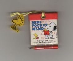 a red pen with a snoopy cartoon on it and a yellow dog charm attached to it