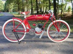 an old red bicycle is parked on the side of the road in front of some trees