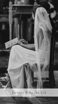 a woman sitting in a chair with a veil over her head and holding a book