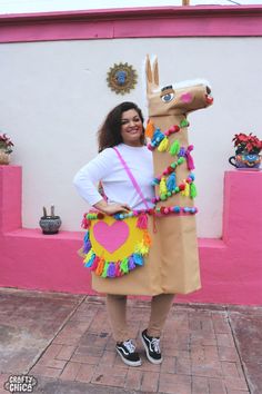 a woman in a costume standing next to a fake horse on the sidewalk with her arms out