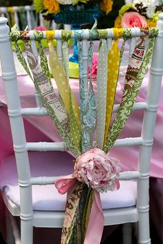 a chair decorated with ribbons and flowers for a wedding or special event, sitting in front of a table