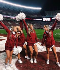 three cheerleaders in red and white outfits on the field at a football game