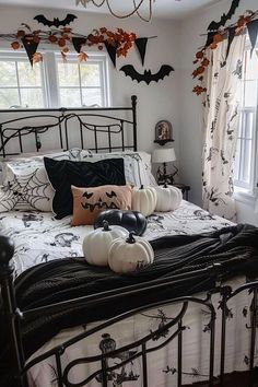 a bedroom decorated for halloween with pumpkins and bats hanging from the ceiling above the bed