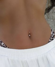 a close up of a woman's stomach wearing a white top and silver necklace