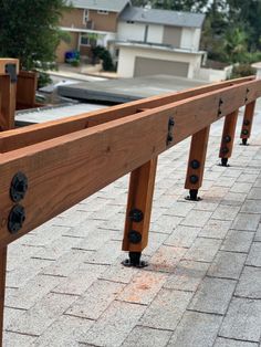 a wooden bench sitting on top of a brick walkway next to a sidewalk with metal studs