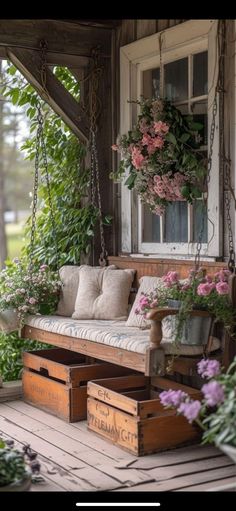 a porch swing with flowers hanging from it and two wooden boxes on the ground below