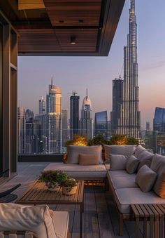 an outdoor living area with couches and tables in front of the cityscape