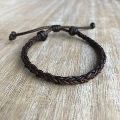 a braided leather bracelet sitting on top of a wooden table