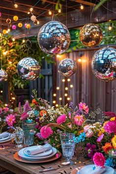 an outdoor dining table with disco balls hanging from the ceiling and flowers in vases