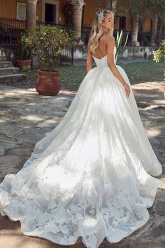 a woman in a white wedding dress standing on the ground with her back to the camera