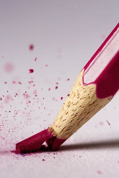 a close up of a pencil with pink crayons on the surface behind it