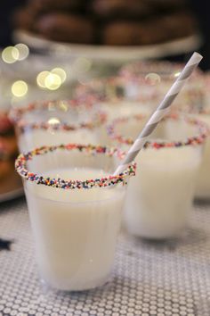 three glasses filled with white liquid and sprinkles on top of a table