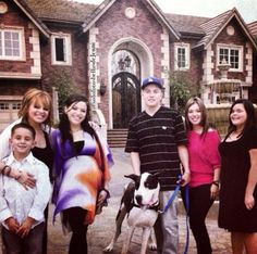 a group of people standing in front of a house with a dog