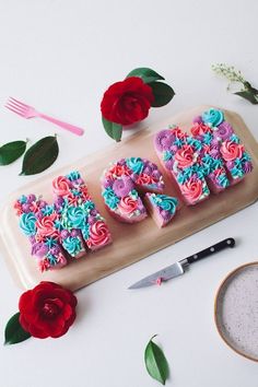 three decorated cupcakes sitting on top of a tray next to scissors and flowers