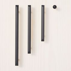 three black handles on a white surface and one has a long handle for the door