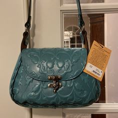 From The Italian Folklore Embossed Collection By Patricia Nash, The Micaela Blue Grass Leather Shoulder Bag Features: 100% Full-Grain Leather Heavy Handcrafted Stitching Signature Hardware Flap With A Swing Latch Closure Faux Suede Lining, 100% Polyester Interior: 1 Zip Pocket And 2 Slip Pockets Exterior: 1 Rear Slip Pocket With Magnetic Snap Closure, Burned Edge Finish Approx. 10" W X 6.5" H X 4.25" D Bag; 18" Strap Drop Blue Saddle Shoulder Bag With Detachable Strap, Blue Saddle Bag With Detachable Strap, Blue Satchel Saddle Bag With Removable Pouch, Blue Rectangular Saddle Bag With Detachable Strap, Blue Saddle Bag Satchel With Removable Pouch, Blue Saddle Bag With Removable Pouch, Blue Saddle Bag With Removable Pouch Satchel, Blue Crossbody Saddle Bag With Detachable Strap, Everyday Blue Flap Bag With Detachable Handle