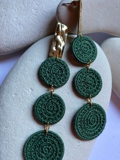 a pair of green earrings sitting on top of a white rock