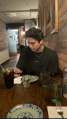 a young man sitting at a table with food and drinks