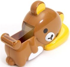 a brown and white bear shaped toy with its mouth open on a yellow object in the shape of a toothbrush holder