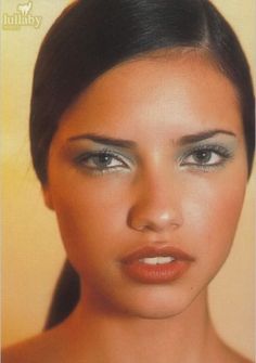 a close up of a woman's face with blue eyeshadow and dark hair