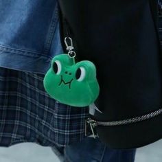 a green frog keychain hanging from the side of a person's jacket