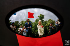 a group of people standing around in front of a mirror with a red flag on it