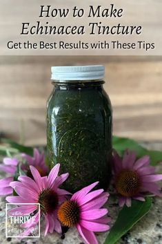 a jar filled with green tea sitting on top of a table next to pink flowers