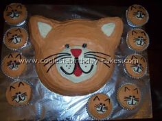 a cake shaped like a cat with nine cupcakes around it's face