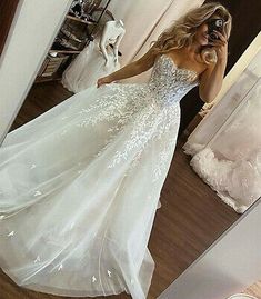 a woman taking a selfie in a wedding dress with flowers on the bouncy skirt