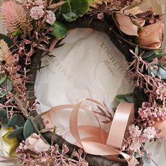 a wreath with pink flowers and ribbons on it