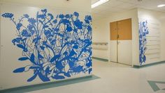 an empty hospital room with blue flowers painted on the wall and white doors in the background