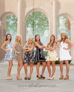 a group of women standing next to each other in front of a building with arches