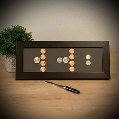 a pen sitting on top of a wooden table next to a framed display with coins