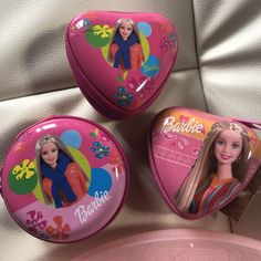 three barbie dolls in pink cases sitting next to each other