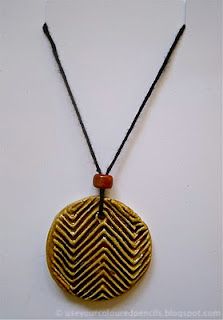 a necklace with an orange bead hanging from it's center, on a black cord