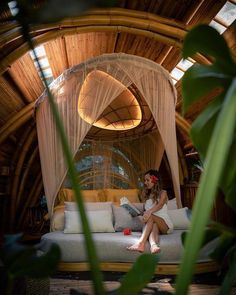 a woman sitting on top of a bed in a room with bamboo walls and ceiling