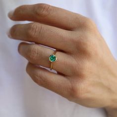 a woman's hand with a gold ring and green stone on the middle finger