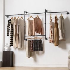 a rack with clothes hanging on it next to a chair and ottoman in a room