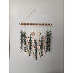 a wall hanging with wooden discs and greenery