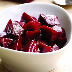 a white bowl filled with sliced beets on top of a table