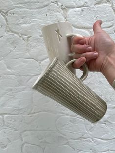 a person holding a coffee cup in their right hand, with the mug hanging from it's ceiling