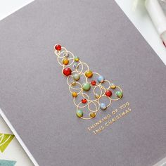 a card with a christmas tree made out of beads and gold wire on top of it