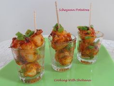 three small cups filled with food on top of a green tray and two sticks sticking out of them