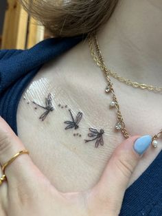 a woman holding her chest with three dragon tattoos on it