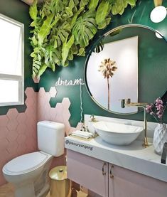 a bathroom decorated in pink, green and gold with palm trees on the wall above the sink